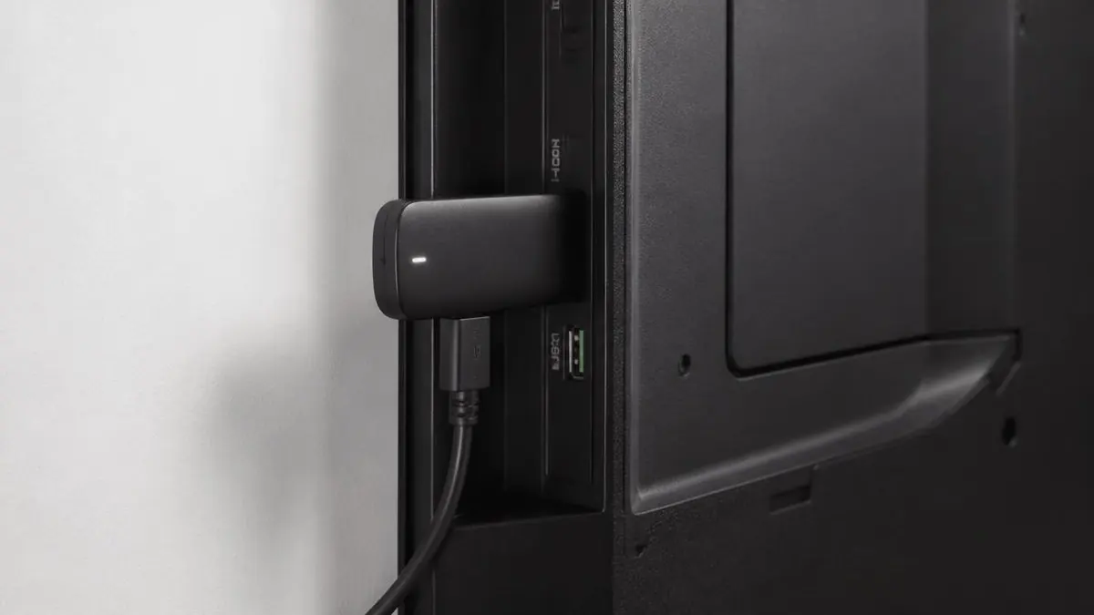 Compact media player connected to the HDMI and USB ports on a wall-mounted television